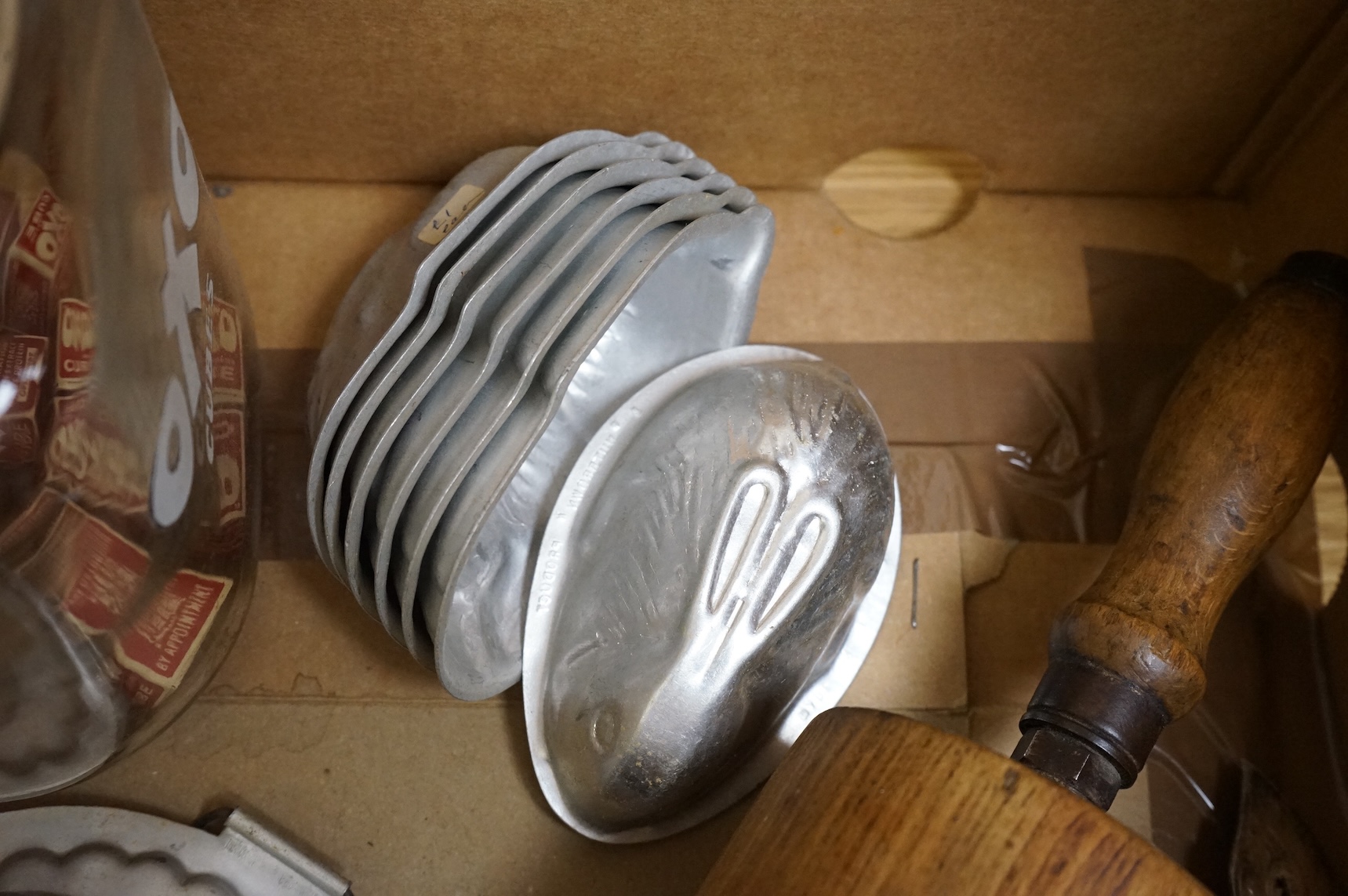 A collection of Kitchenalia, including a Wade novelty teapot, a large wooden rolling pin, jelly moulds, etc.